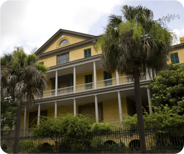 Yellow three-story house next to palm trees in Aiken, SC